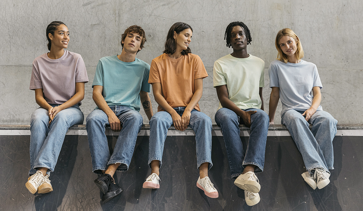Cinq mannequins hommes et femmes posent de façon décontractée et portent les t-shirts bio Creator dans des teintes pastels