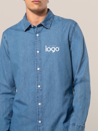 Un homme porte une chemise en jean bleue à manches longues, personnalisée d'un logo sur la poitrine