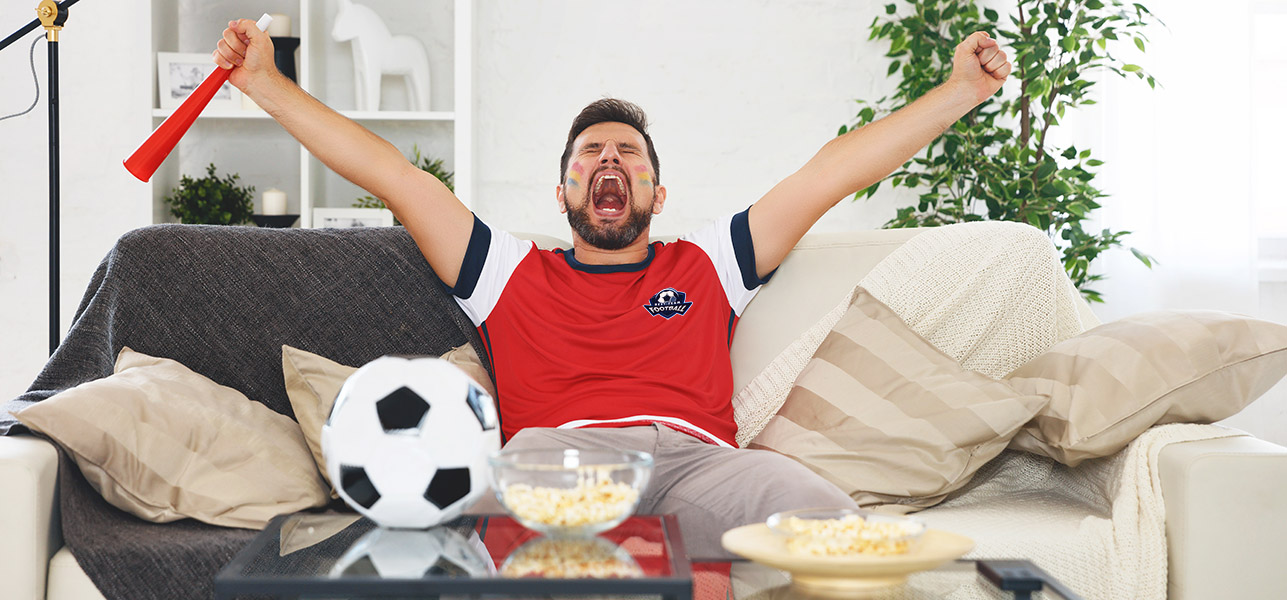 Un supporter de foot célèbre une victoire sur son canapé avec un t-shirt personnalisé