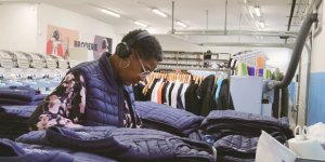 Une femme réalise les finitions de broderies sur des doudounes
