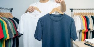 Un homme incite à choisir entre un t-shirt blanc et un t-shirt bleu
