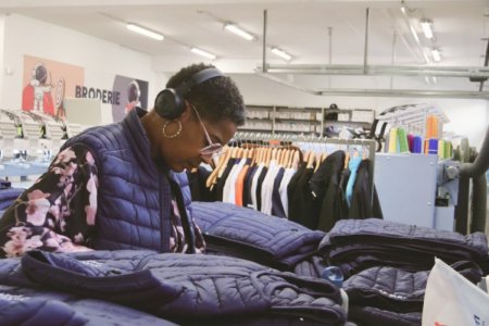 Une femme réalise les finitions de broderies sur des doudounes