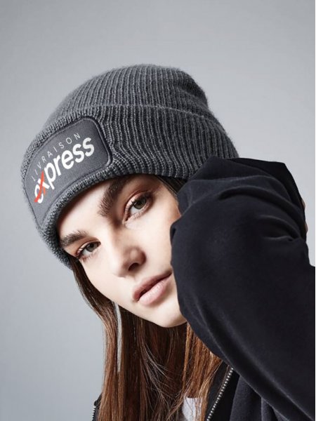 une femme porte le bonnet à personnaliser en couleur grey avec votre logo 