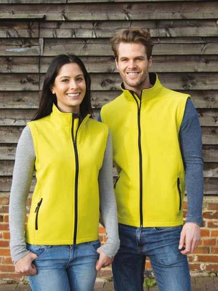 Une femme et un homme portent les bodywarmers softshells R232F et R232M en coloris Yellow / Black