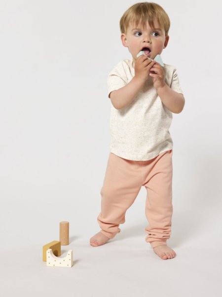un bébé portant le jogging Baby Tumbler à personnaliser dans le coloris Fraiche Peche