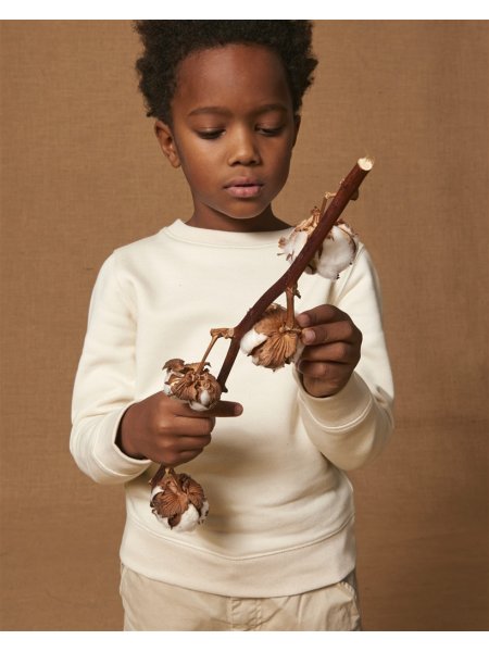 Un enfant tient une branche de coton et porte le sweat col rond Mini Changer en coton bio dans le coloris Natural Raw