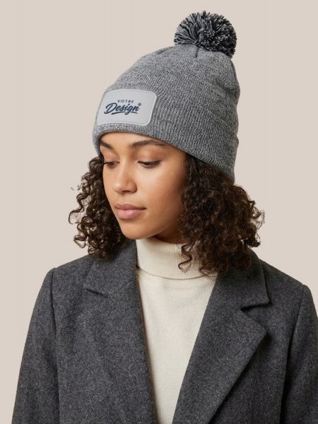 Bonnet à pompon personnalisé Snowstar Patch B443 Heather Grey / Black porté, personnalisé avec votre design brodé sur le patch Bonnet à pompon personnalisé Snowstar Patch B443 Heather Grey / Black porté, personnalisé avec votre design brodé sur le patch