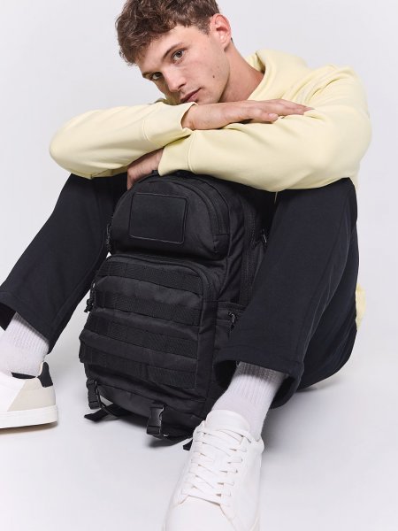 Sac à dos tactique urbain personnalisable KI0179 porté par un mannequin homme assis