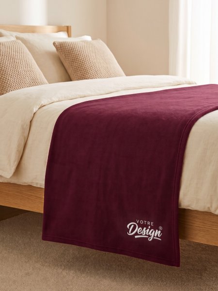 Mise en situation plaid en polaire personnalisable KP424 coloris Wine au pied d'un lit, brodé avec votre design Mise en situation plaid en polaire personnalisable KP424 coloris Wine au pied d'un lit, brodé avec votre design