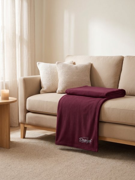 Mise en situation plaid en polaire personnalisable KP424 coloris Wine plié sur un canapé, brodé avec votre design Mise en situation plaid en polaire personnalisable KP424 coloris Wine plié sur un canapé, brodé avec votre design